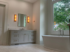 grey bathroom renovation with tub under large window and tiled floors