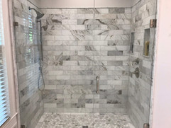 bathroom remodeling project with floor to ceiling grey tiled shower and inset shelving