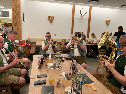 Die Outback Bradler sitzend und musizierend am Tisch eines Buschenschankes