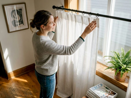 Woman adjusting sheer curtains showing heading