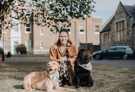 Lara the dog trainer is sat with two dogs, one golden Labrador and a black Sharpei
