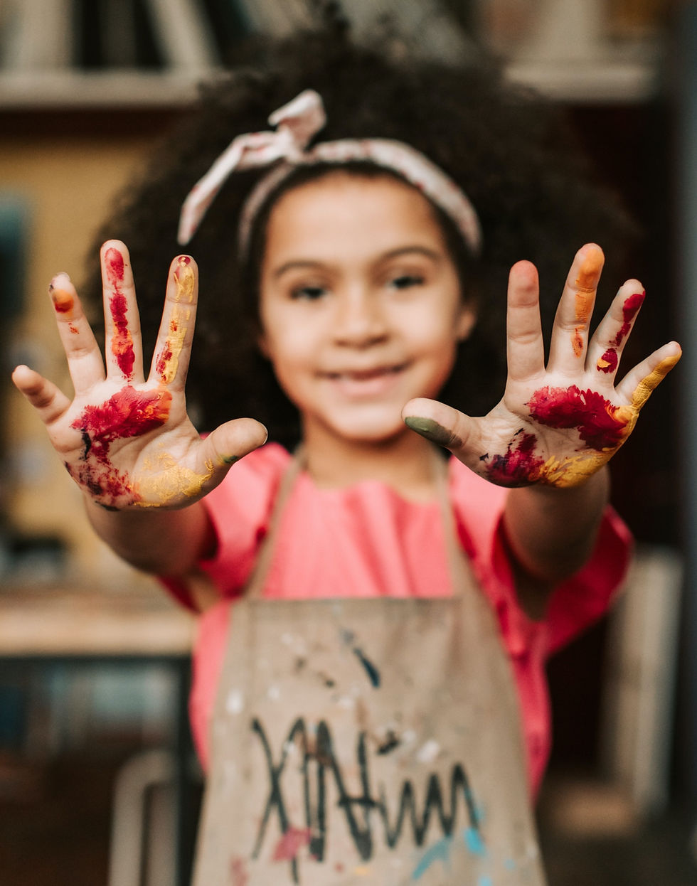 Menina com as mãos sujas de tinta