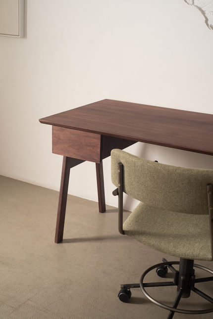 Side view of the Nonno Desk and its drawer with a sage upholstered office chair tucked in