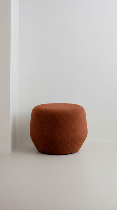 Puff Surrey pequeno em tecido terracota, em ambiente com parede clara