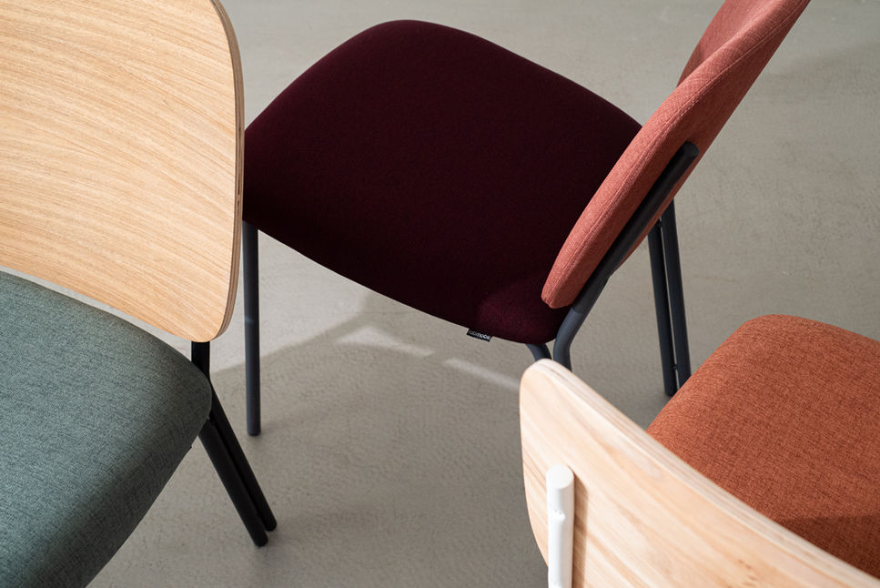Overhead detail of Madalena Chair seats in burgundy, sage and terracotta fabric beside natural wood veneer backrests