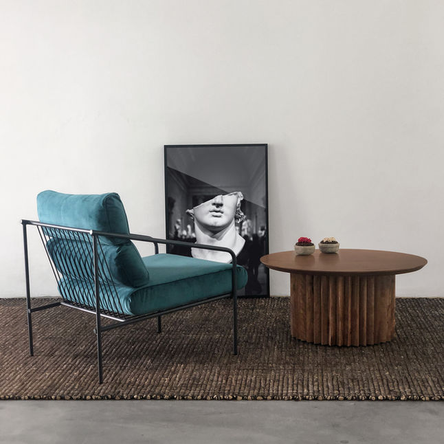 Helsinki coffee table with natural wood top holding two small decorative bowls, next to a teal velvet armchair and a framed black and white photograph