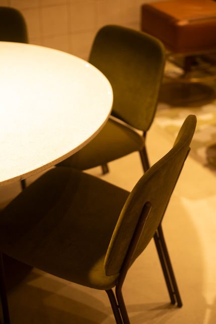 Two olive Madalena Chairs at a round terrazzo café table under soft warm lighting
