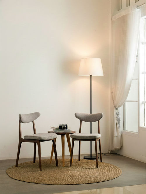 Par de Cadeiras Ávila em madeira maciça escura com estofado em tecido cinza, ambientadas ao lado de mesa lateral com luminária de piso, sobre tapete de fibra natural