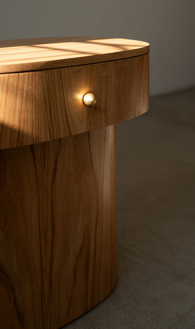 Detail of the natural wood Vis Nightstand showing the polished brass knob, the shadow gap under the drawer and the continuous grain of the base