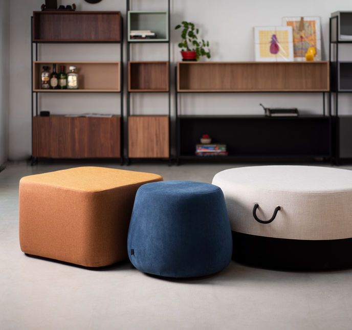 Orange Composé Ottoman with a mustard top beside a small blue ottoman and a large round two-tone ottoman