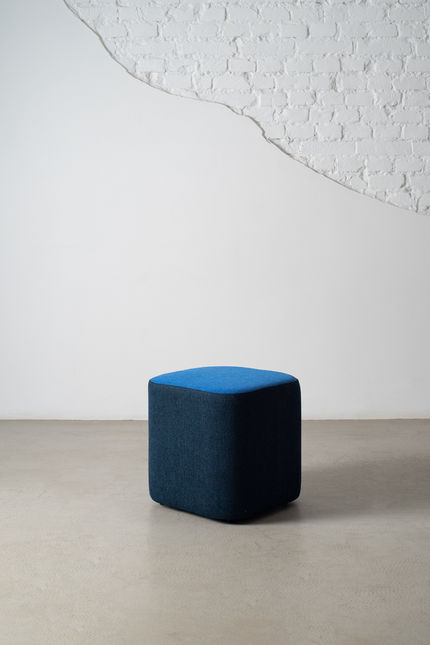 Composé Ottoman with navy sides and a bright blue top, shown alone against a white wall