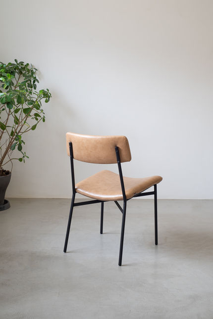 Rear view of the tan Luiza Chair, showing the curved seat and the slim black steel structure