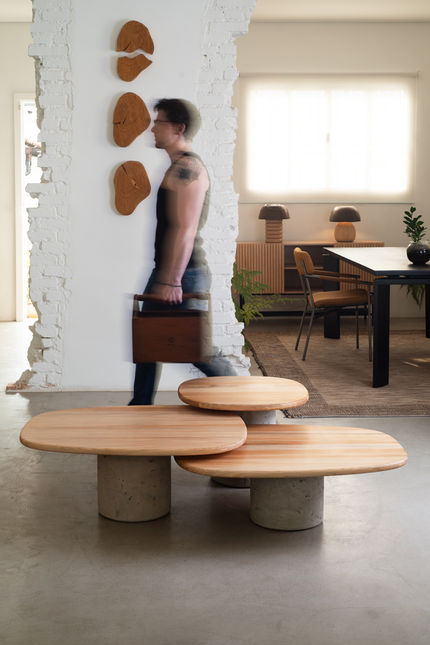 Set of three Creta Coffee tables with wooden tops in a loft interior, with a person walking past a brick pillar