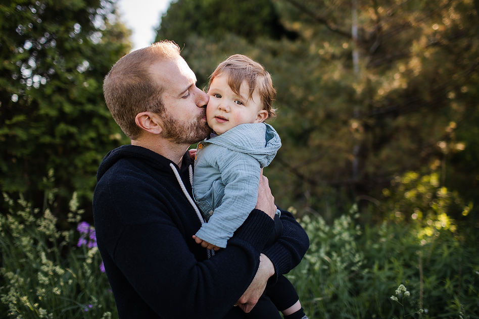Dad holding infant son, kissing him on the cheek