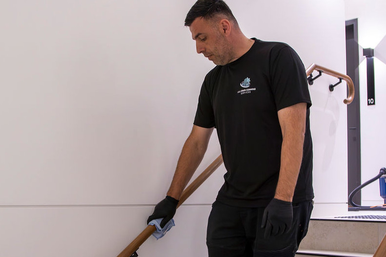 Man cleaning stairwell hand railing