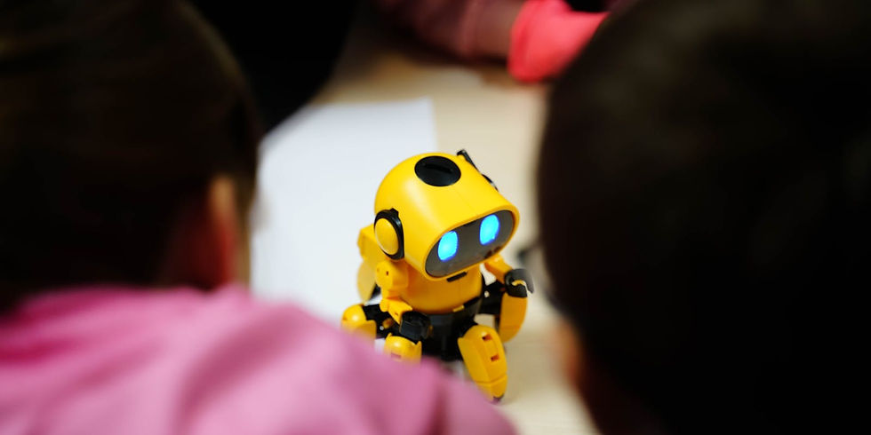 A small yellow robot with glowing blue eyes is on a table, surrounded by children in pink and dark clothing, creating a curious atmosphere.