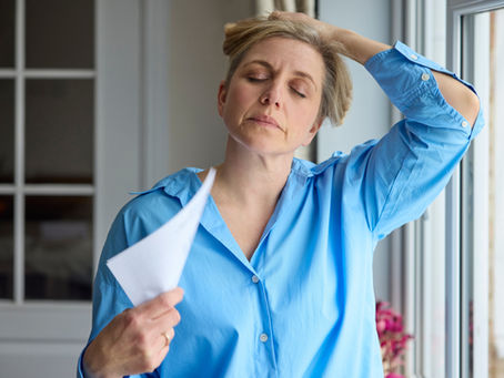 Woman fanning herself as she has a hot flash
