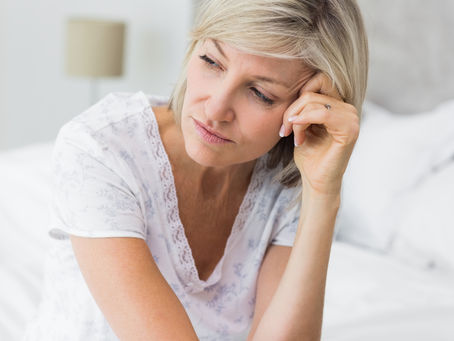 Midlife woman sitting beside her bed after a restless night.