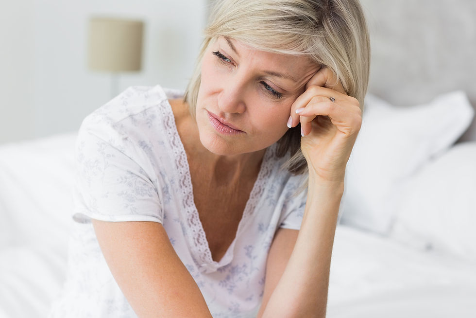 Midlife woman sitting beside her bed after a restless night.