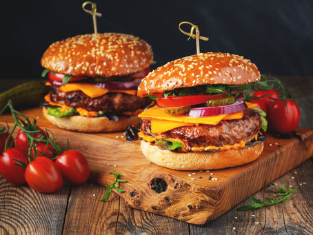 Burger on an outdoor picnic table representing alpha-gal syndrome, a tick bite–related meat allergy.