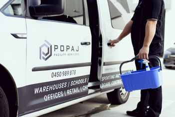 Man exits the POPAJ Facility Services van carrying cleaning supplies for services.