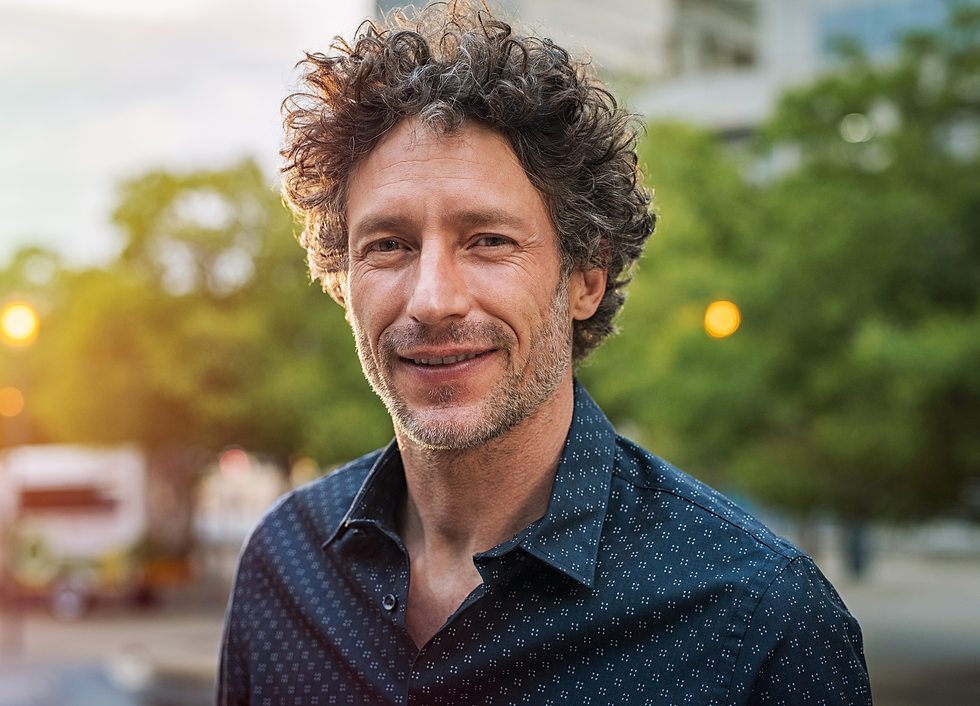 Hombre de mediana edad sonriente en exterior, imagen asociada a recuperación emocional y bienestar masculino.