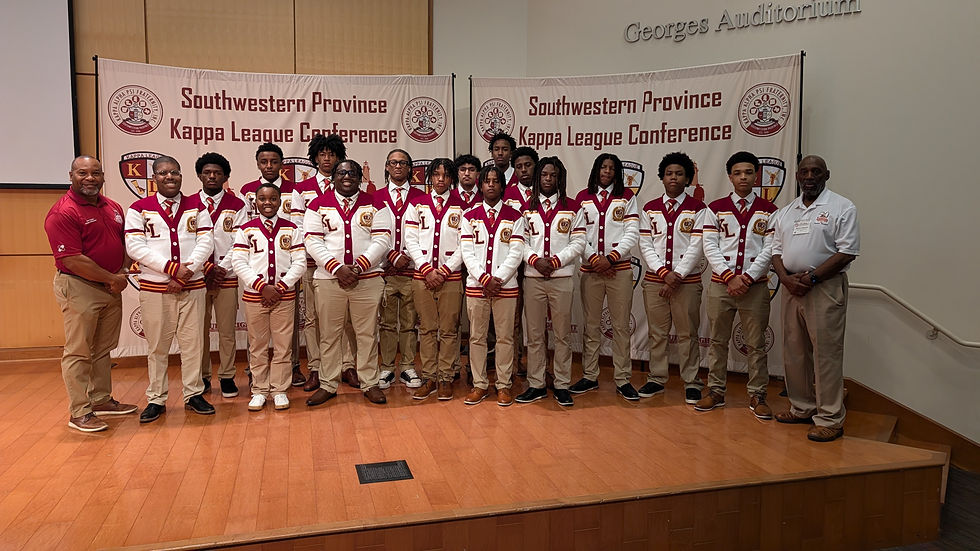 A group of Kappa League members wearing matching white and maroon letterman-style jackets and khaki pants stand on a stage with two adult mentors in front of banners that read “Southwestern Province Kappa League Conference.