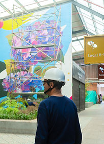 Persona con casco blanco mirando un vibrante mural de hortensias. Murales artísticos.