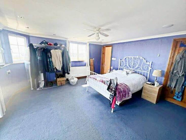 A bedroom with a bed and a ceiling fan