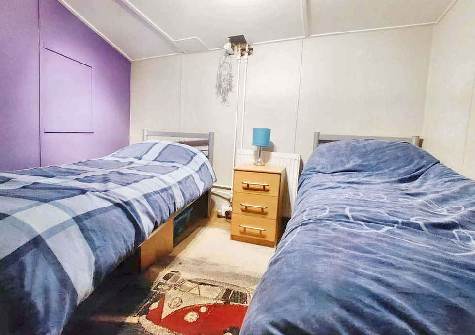 Two beds in a small room with purple walls, creating a cozy and inviting atmosphere.