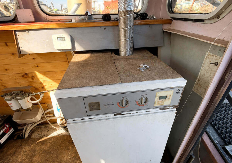Solid fuel boiler installed inside project houseboat wheelhouse with utility connections.
