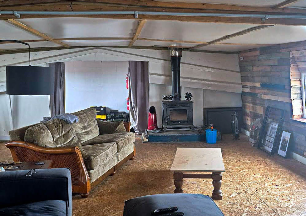 Cozy living room on a houseboat with wood-burning stove, sofas, and rustic wood-paneled walls.