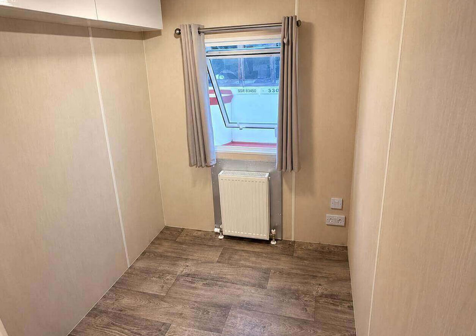 Bright cabin aboard houseboat with fitted storage, radiator and window.