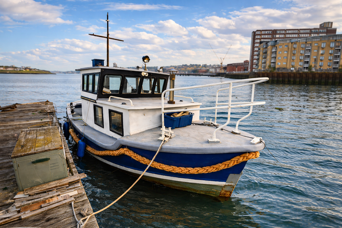 White and blue boat docked at a pier on a sunny day.