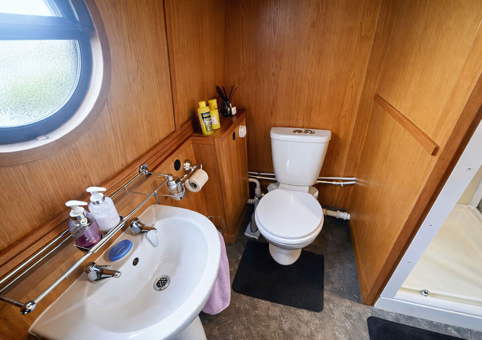 Separate toilet and sink area in the narrowboat bathroom with wood-paneled walls and modern fixtures.