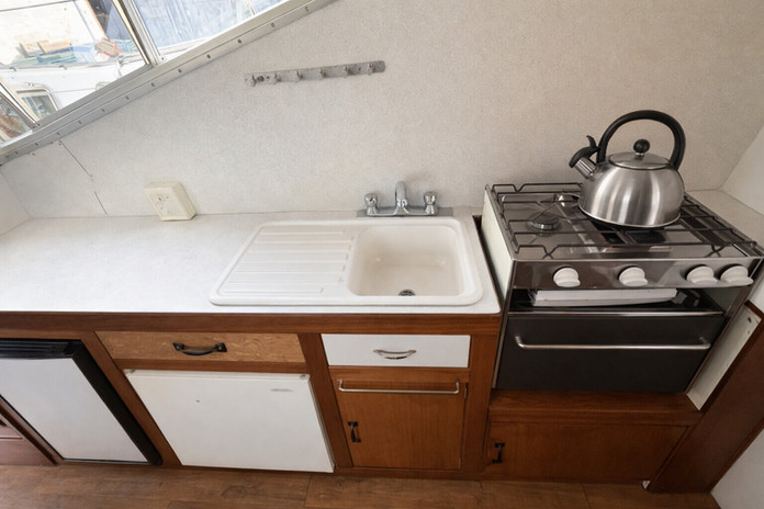 Compact boat kitchen with sink, stove, and cabinets