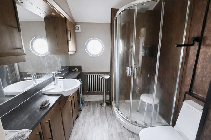 Small bathroom featuring a glass shower, vanity sink, and porthole windows.
