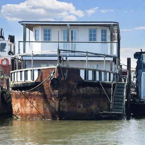 White two-story houseboat on rusty hull