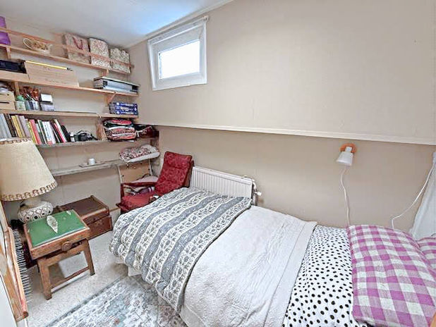 Cozy bedroom with bed, books, shelves, and small window in a house.