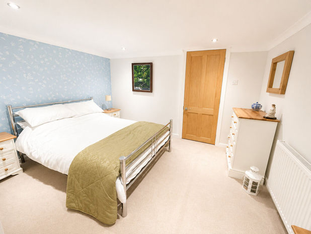 Cozy bedroom with a large bed, light blue accent wall, and wooden door