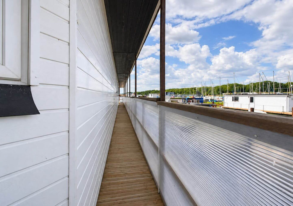 Covered side deck aboard Perch houseboat with views across the marina.