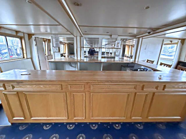 Spacious wooden bar counter inside a boat with blue patterned carpet.
