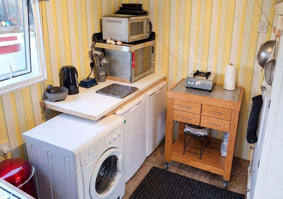 Kitchen area aboard Peggy Rose with washing machine, fridge and cooking appliances.