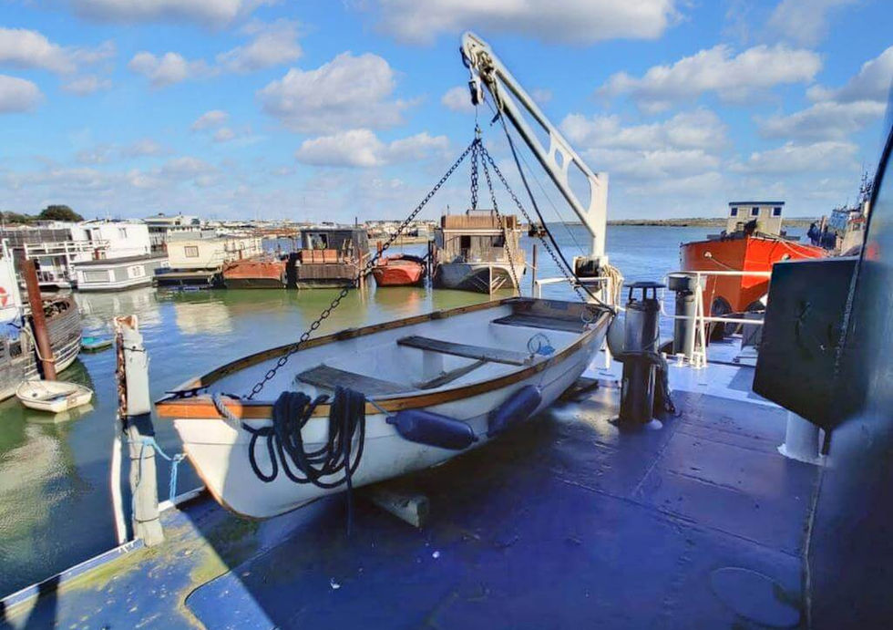 A boat is being lifted onto a dock by a crane, with water and a clear sky in the background.