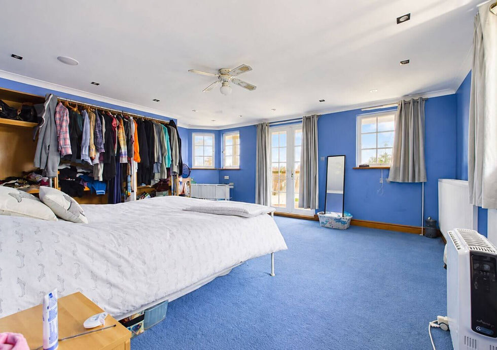 Large double bedroom aboard Perch houseboat with blue walls and multiple windows.