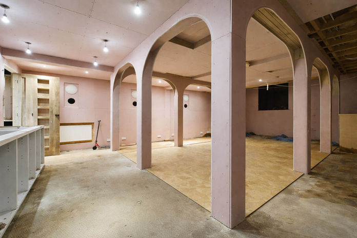 Spacious room with pink arched walls and concrete floor