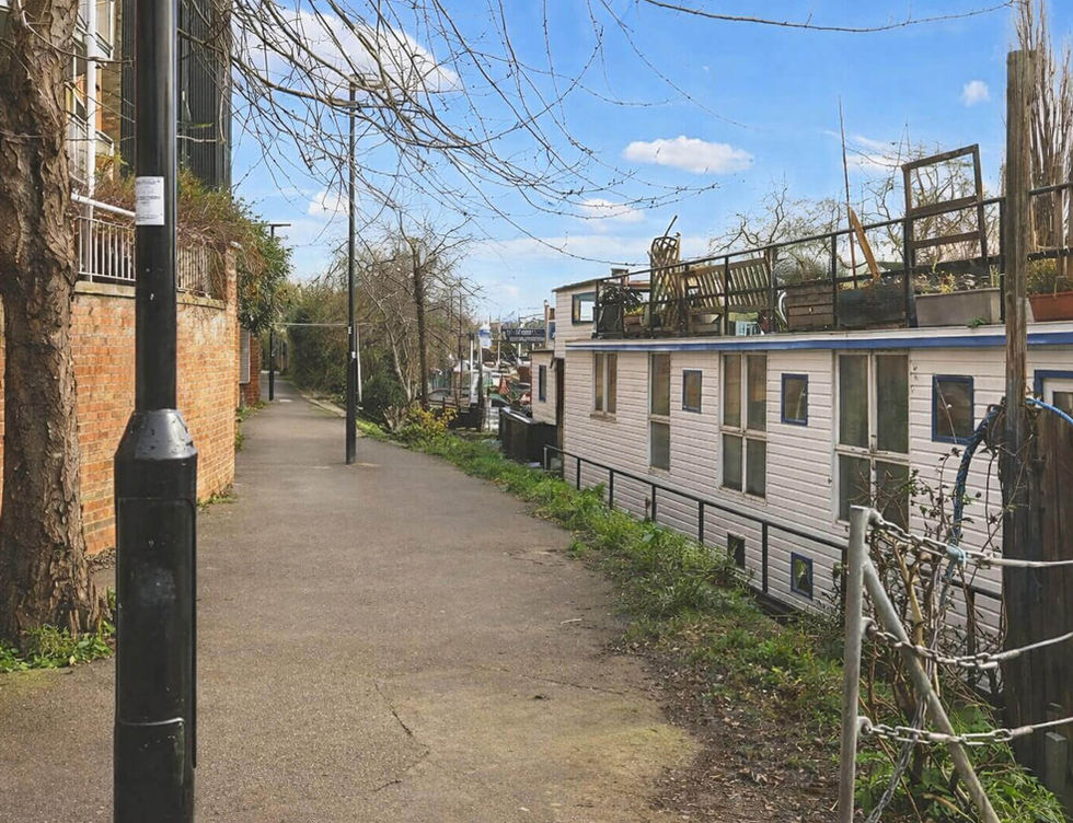 Floating home beside a riverside walkway in a peaceful London canal setting