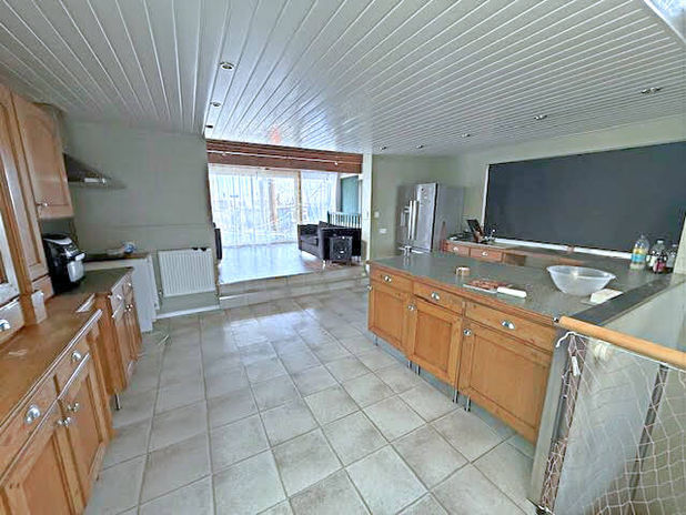 Spacious kitchen with wood cabinets, island, and large glass door leading outside.