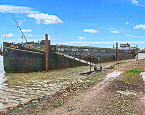 Barge with ramp docked at a muddy riverbank