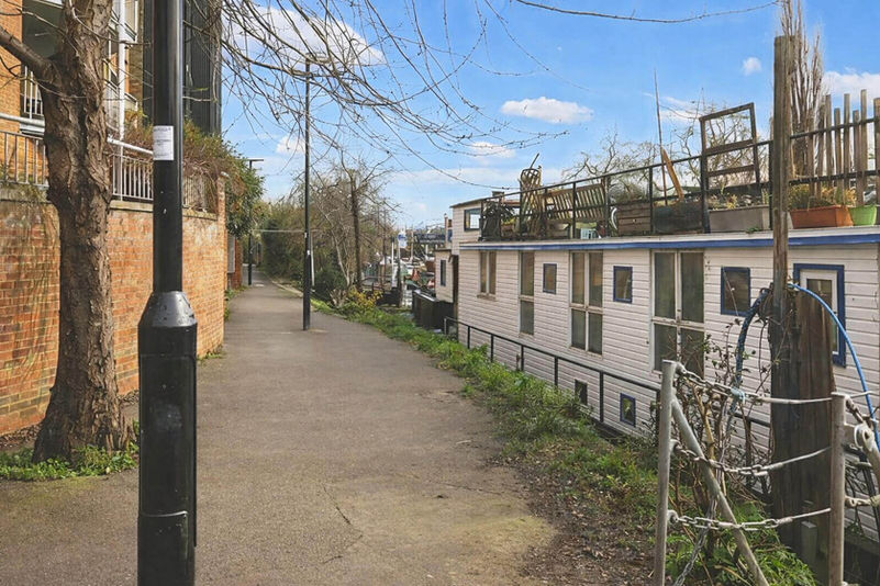 Paved path next to houseboats at a London mooring.